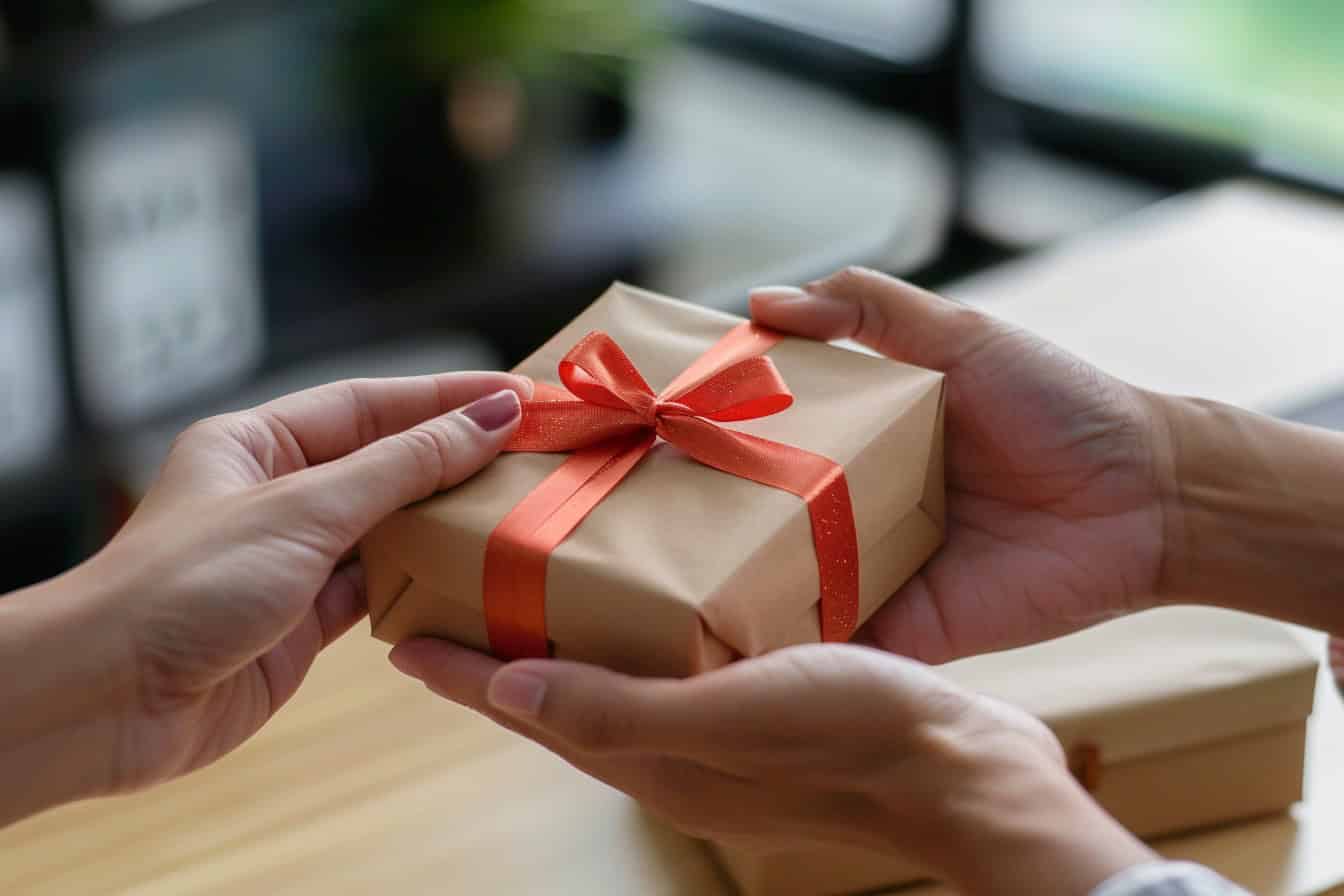 Hände übergeben ein sorgfältig verpacktes Geschenk an eine andere Person, symbolisiert eine Schenkung sowie eine mögliche Rückforderung wegen groben Undanks.
